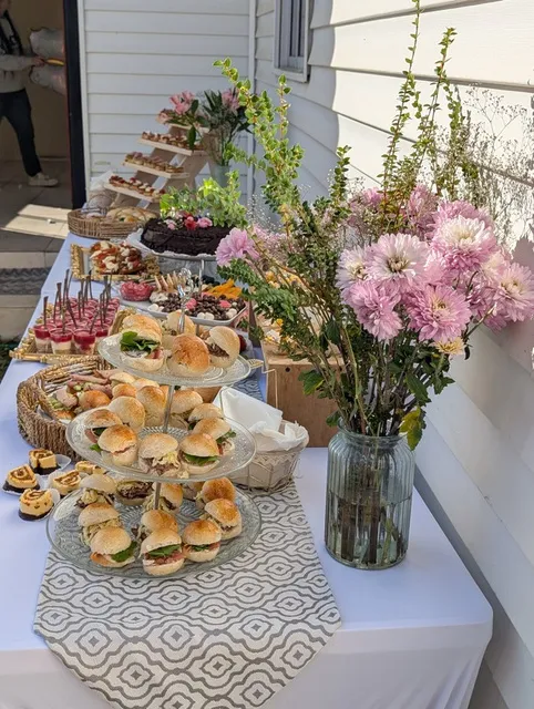 Mesa de cóctel montada con flores y bandejas de bocados